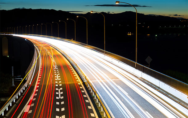 busy highway with car headlights flying by in streaks at dusk